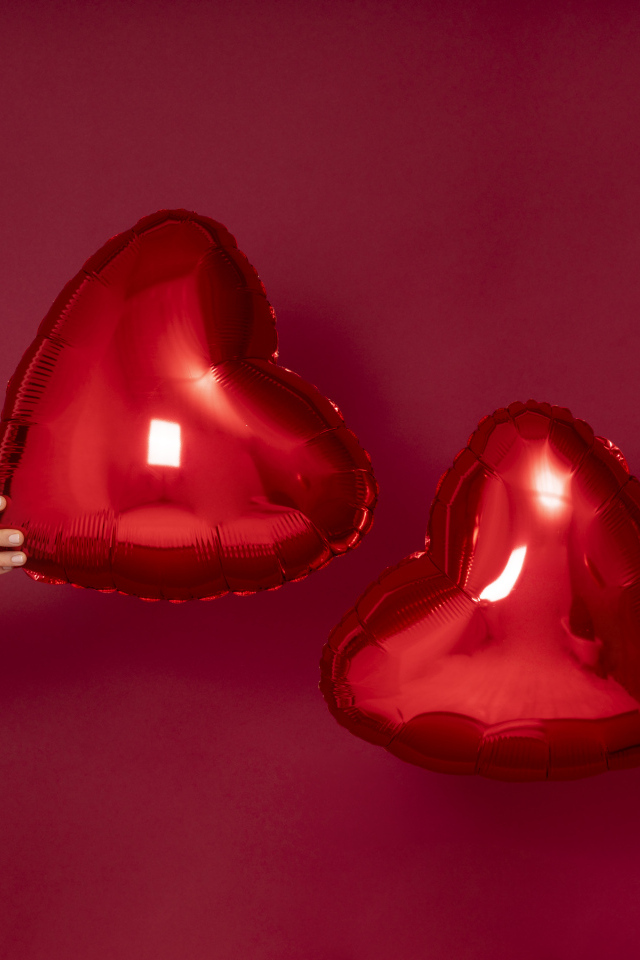 Два воздушных шара в форме сердца на красном фоне