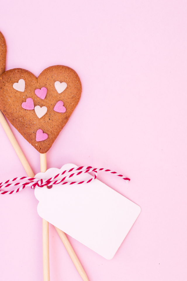 Два сердечка на палочке на розовом фоне
