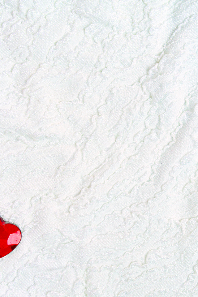 Два красных сердца из пластика на белой ткани