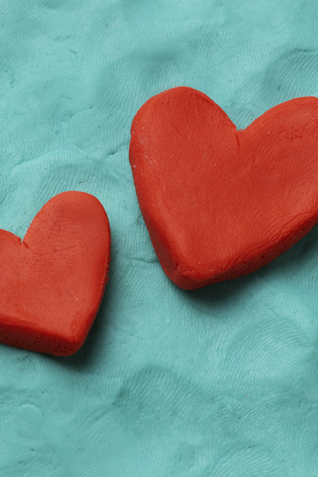 Два красных сердца из пластилина на голубом фоне