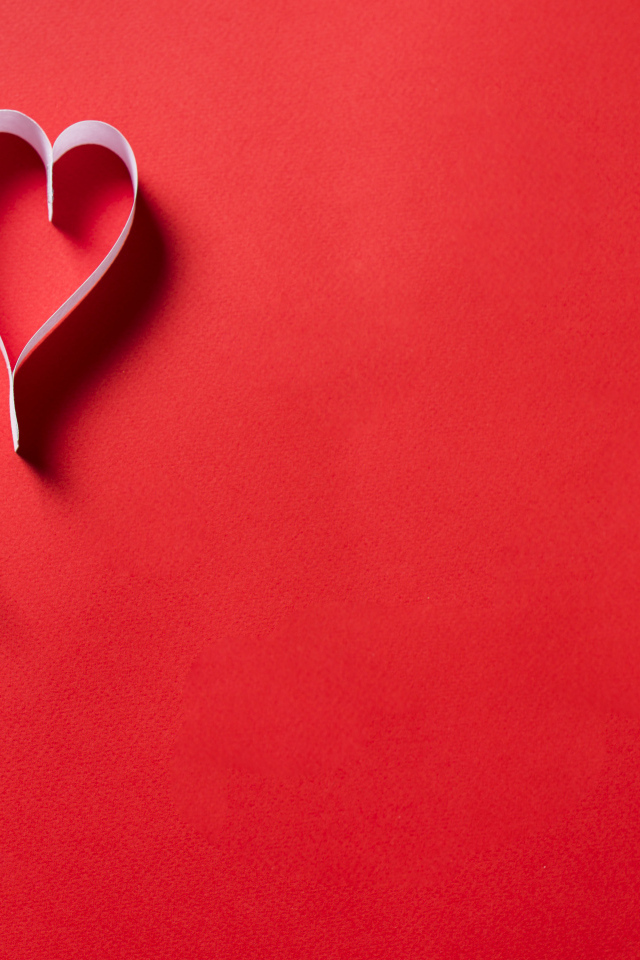 Два белых бумажных сердца на красном фоне