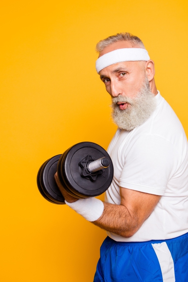 Спортивный мужчина с гантелей в руке на желтом фоне