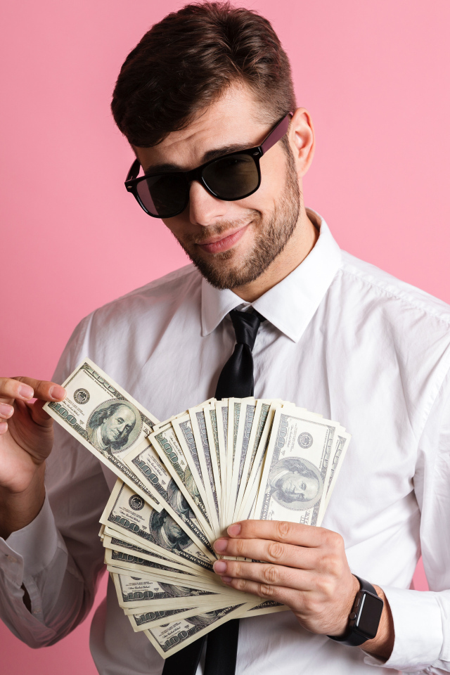 Деловой мужчина в черных очках с пачкой денег на розовом фоне