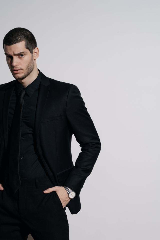 Красивый деловой мужчина стоит у серой стены