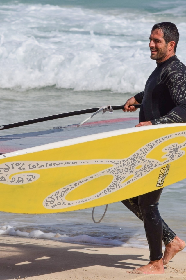 Мужчина серфер с доской на пляже