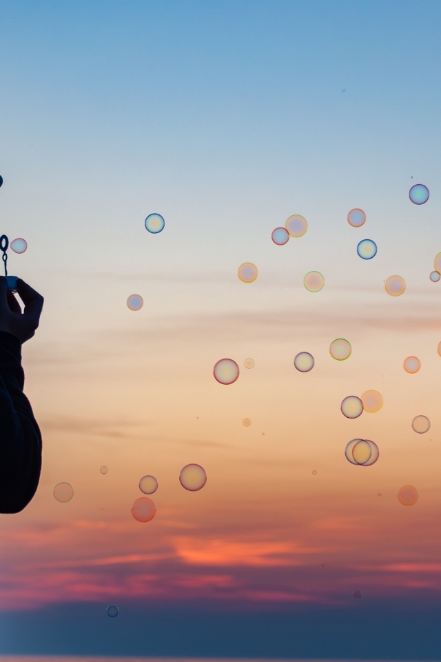 Мужчина пускает мыльные пузыри на закате