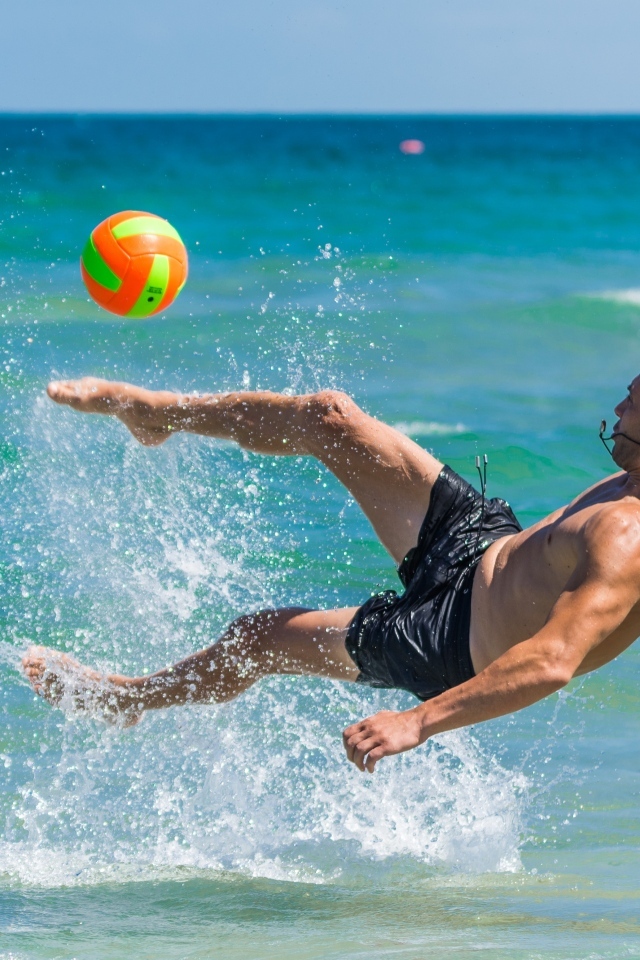 Мужчина играет в пляжный футбол