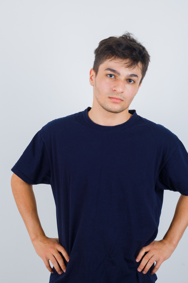 Молодой парень в синей футболке на сером фоне