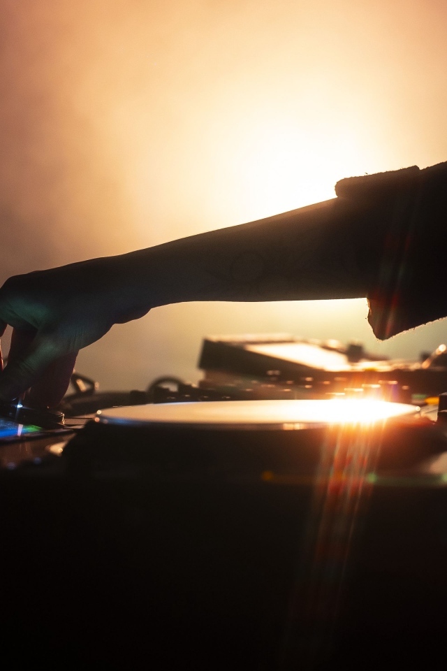 Рука диджея настраивает музыкальный пульт 