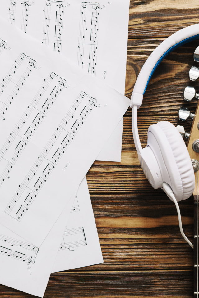 Ноты, наушники и гитара на столе