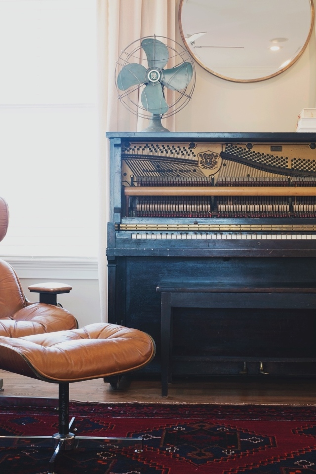 Старое пианино в комнате с кожаным креслом