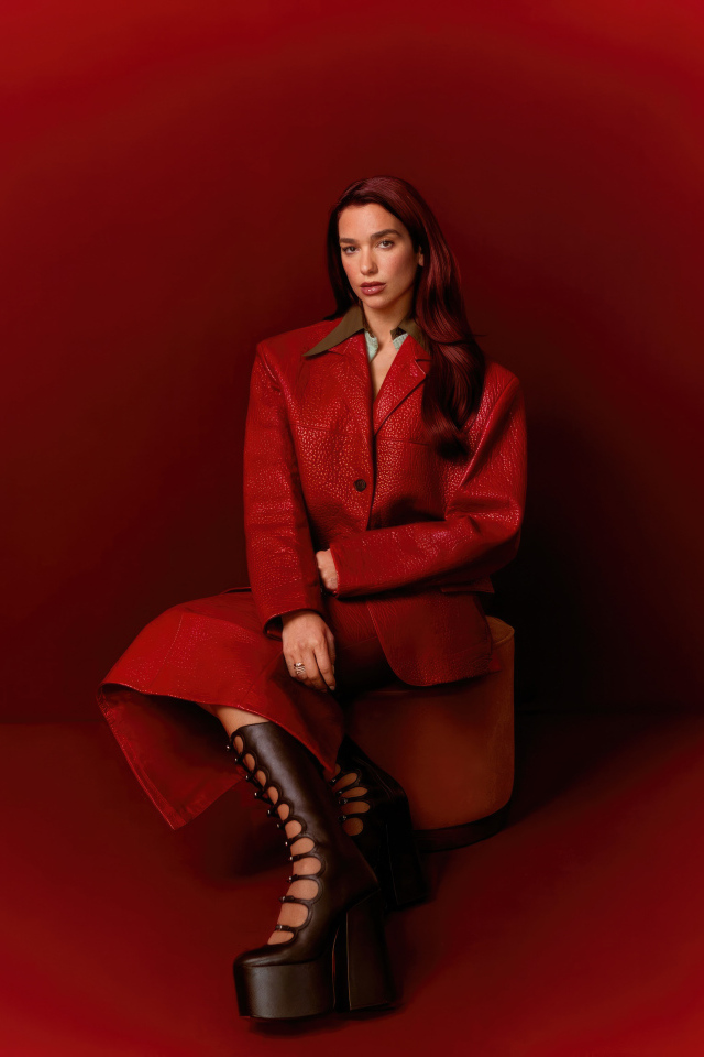 Певица Дуа Липа позирует на красном фоне