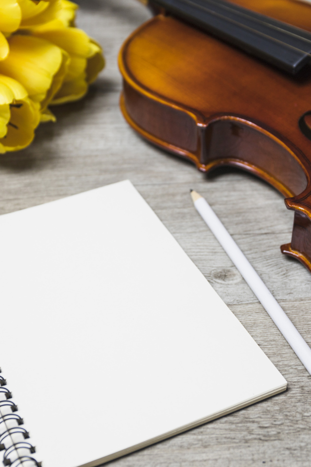 Скрипка, блокнот и желтые тюльпаны на столе