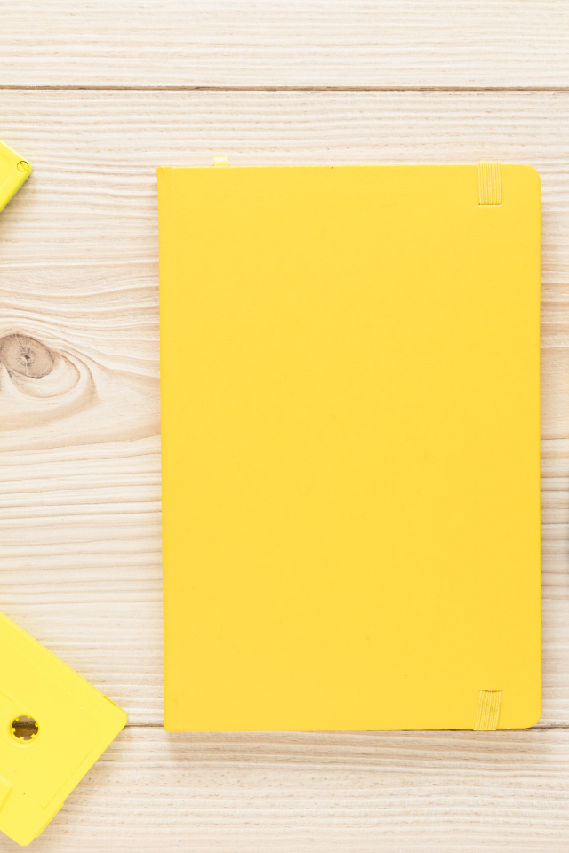 Желтый блокнот с ручкой и кассетами на столе