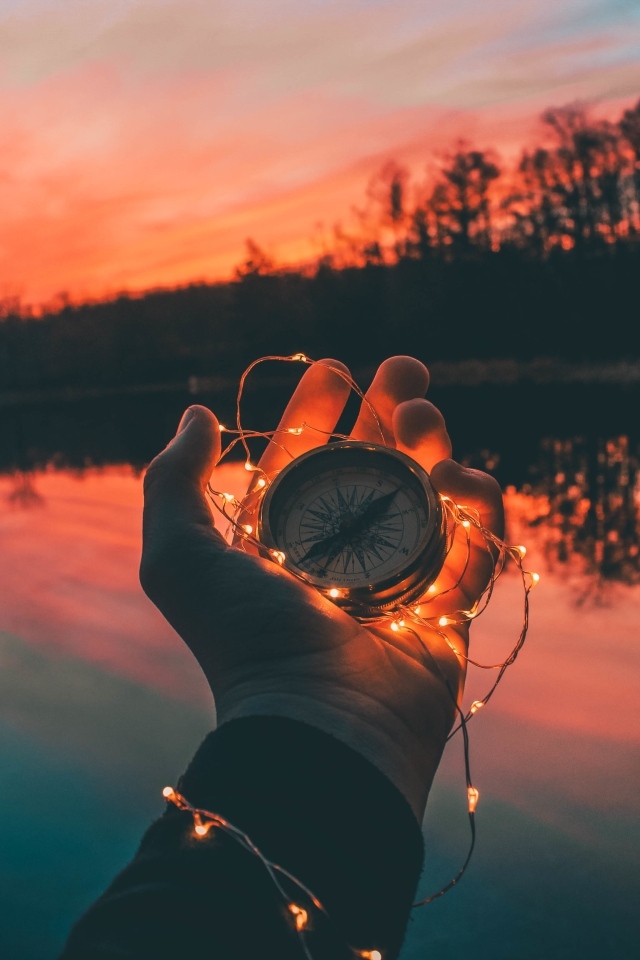 Компас с гирляндой в руке у реки