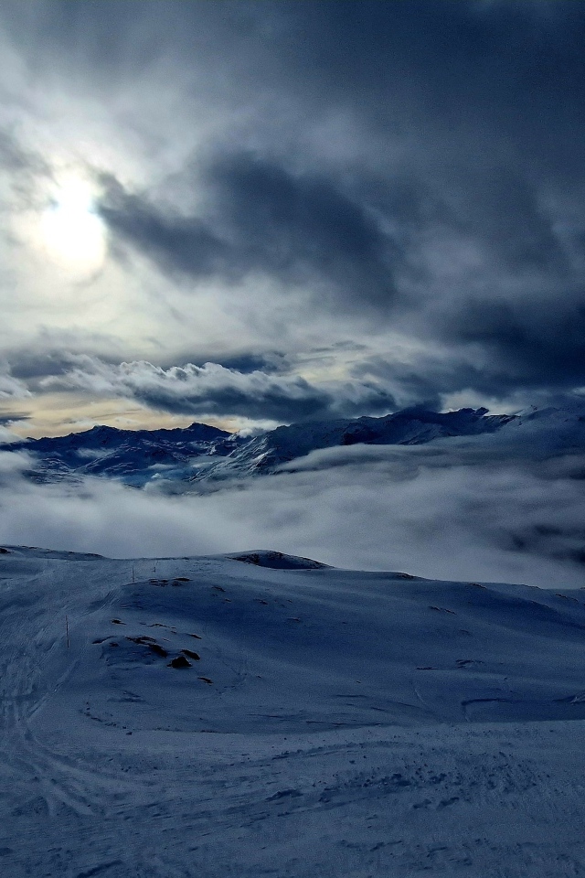 Луна в облачном небе над заснеженными горами