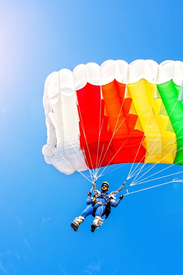 Парашютист в голубом небе в лучах солнца