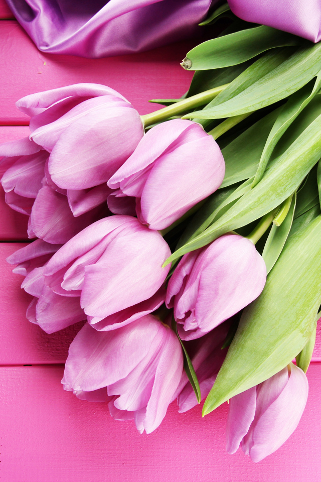 Красивый букет тюльпанов с лентой на розовом столе