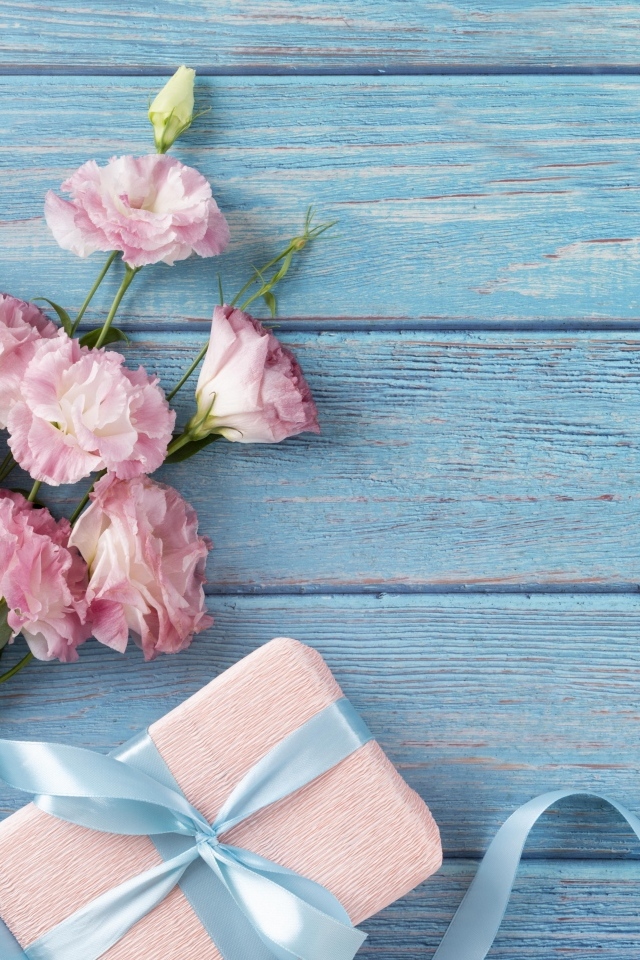 Букет розовой эустомы с подарком на голубом фоне