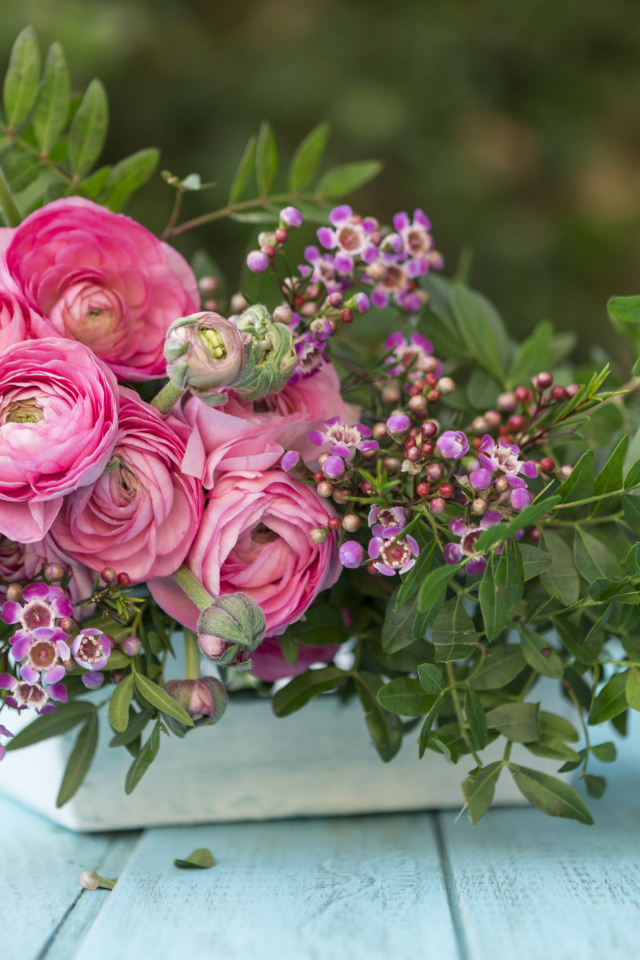 Букет розовых цветов лютика в ящике на голубом столе