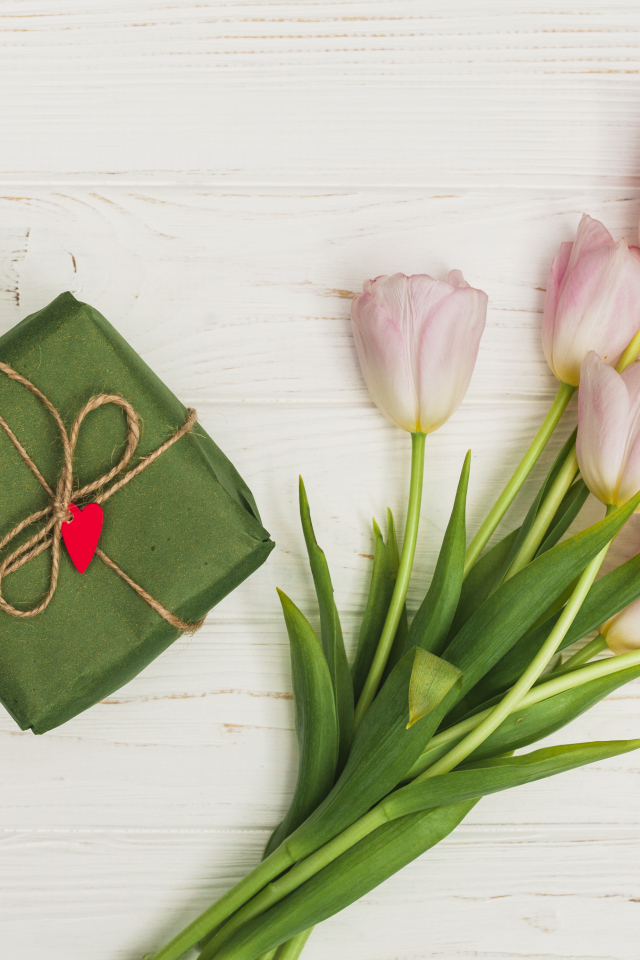 Букет розовых тюльпанов на столе с подарком