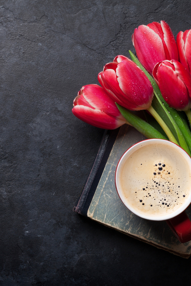 Букет красных тюльпанов с чашкой кофе на черном столе