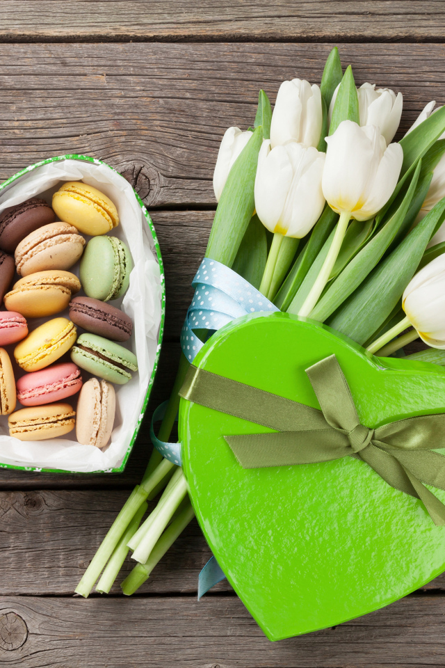 Букет белых тюльпанов на столе с коробкой печенья макарун