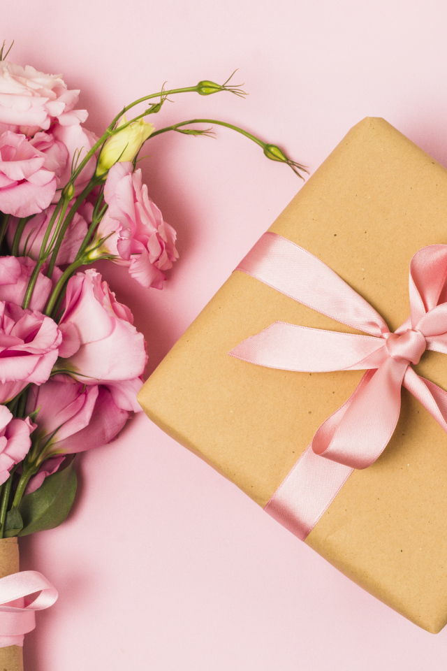 Большой букет эустомы с подарком на розовом фоне