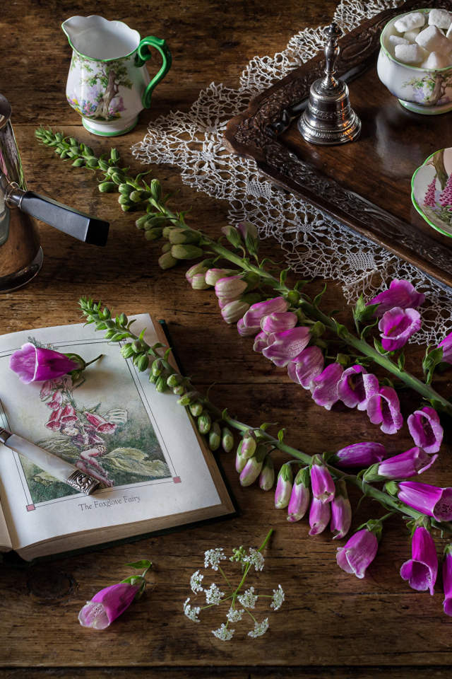 Розовые цветы на столе с книгой и чаем