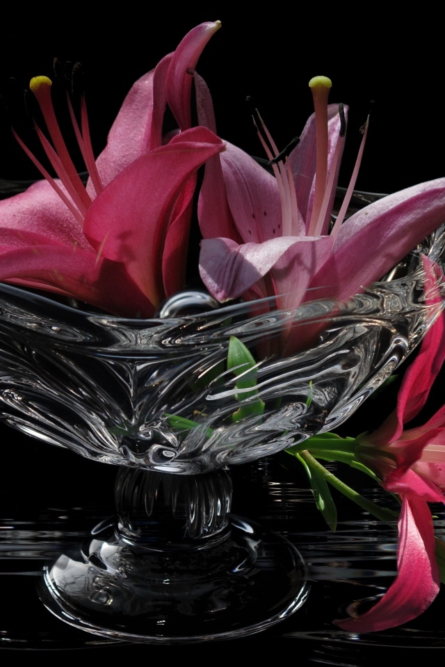 Розовые лилии в стеклянной вазе на столе