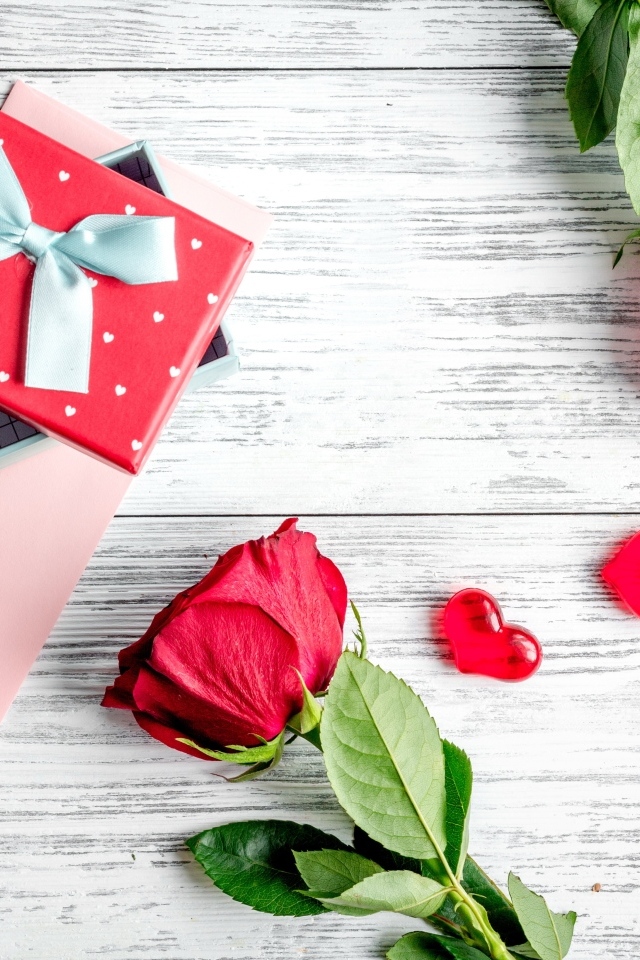 Две красные розы с подарком и сердечками на столе