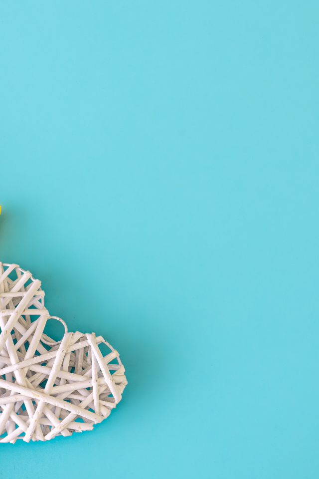 Белое плетеное сердце с букетом желтых тюльпанов на голубом фоне