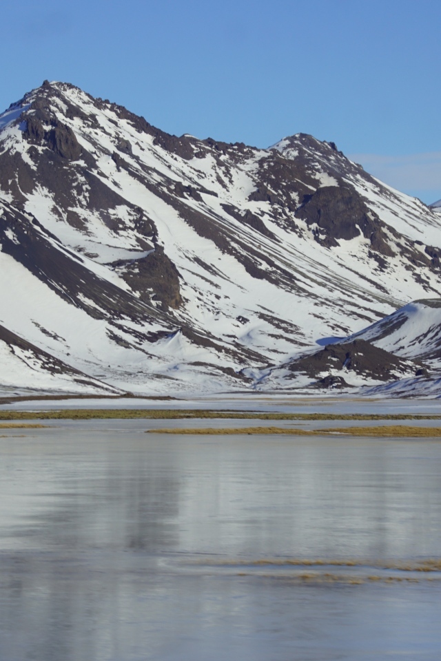Горы в снегу под голубым небом у воды
