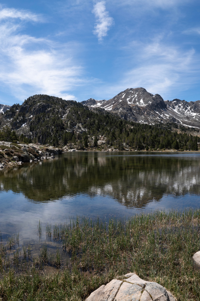 Горы отражаются в воде озера с большими камнями