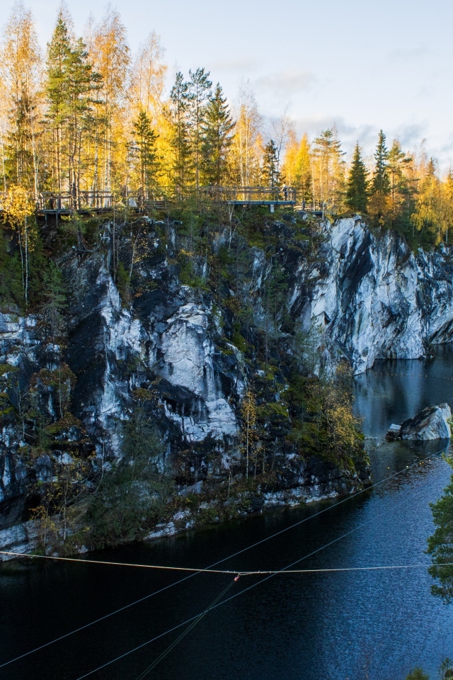 Вид на утес покрытый деревьями у воды