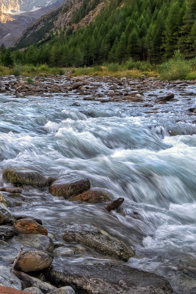 Быстрая холодная река стекает по камням в горах 