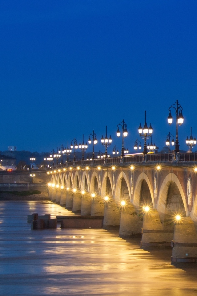 Красивый светящийся мост через реку ночью 