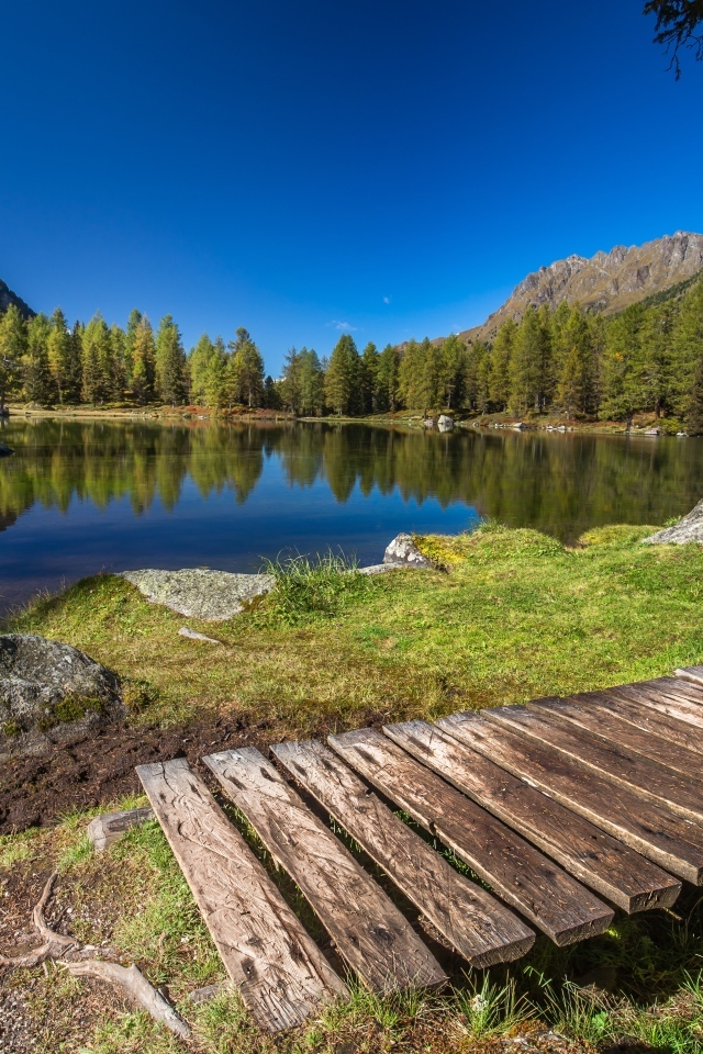Мост на берегу озера в горах под голубым небом