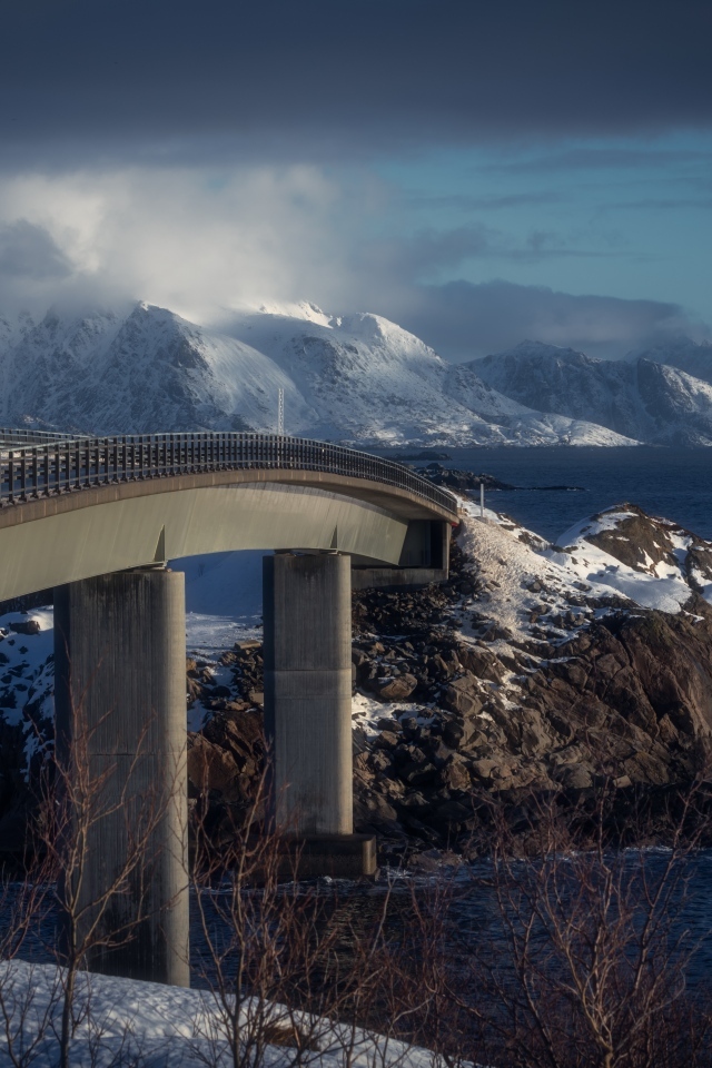 Мост через реку в заснеженных горах 