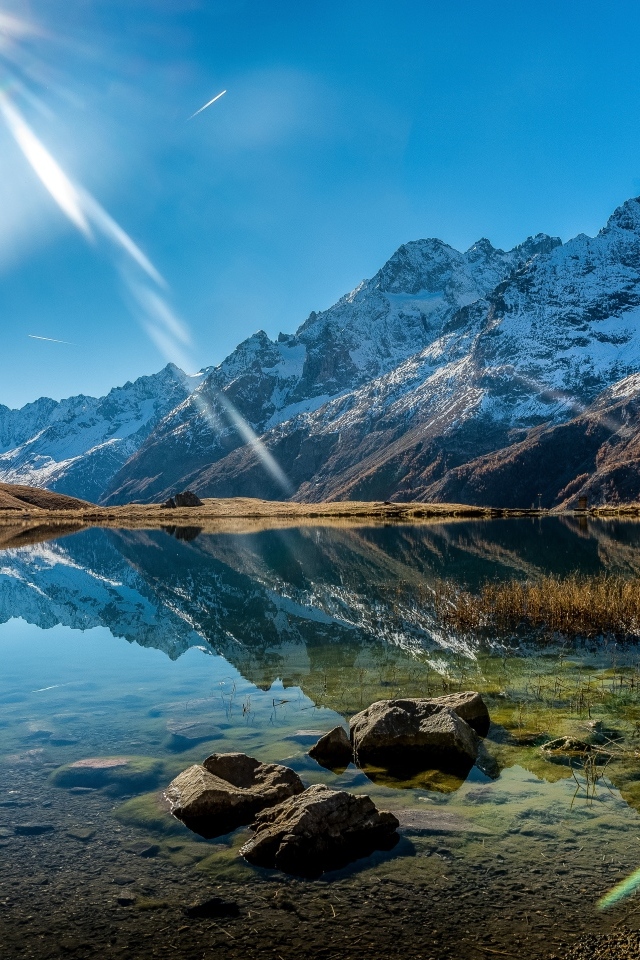 Лучи яркого солнца освещают гору и озеро