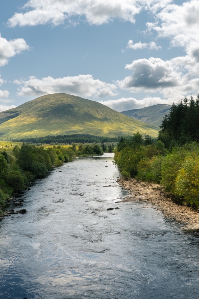Белые облака в голубом небе над рекой в горах