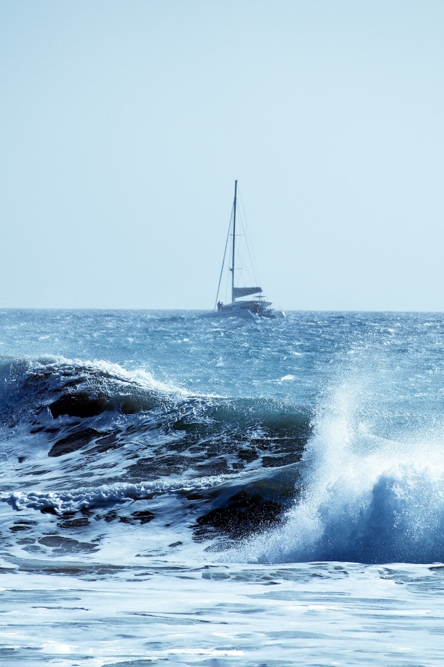 Бушующие морские волны с парусным судном на горизонте