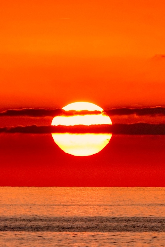 Яркое солнце в облаках на закате над морем 