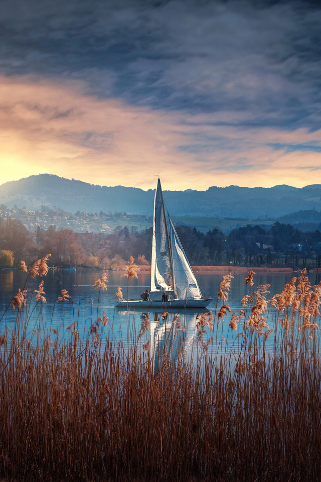 Парусная лодка на озере на закате солнца