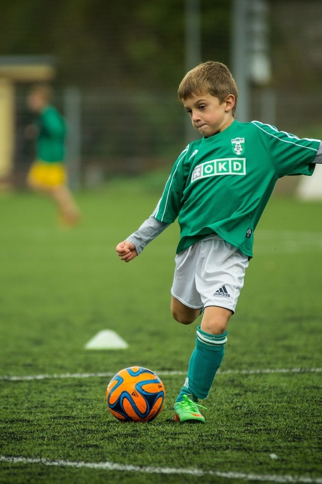 Мальчик в форме играет на поле в футбол