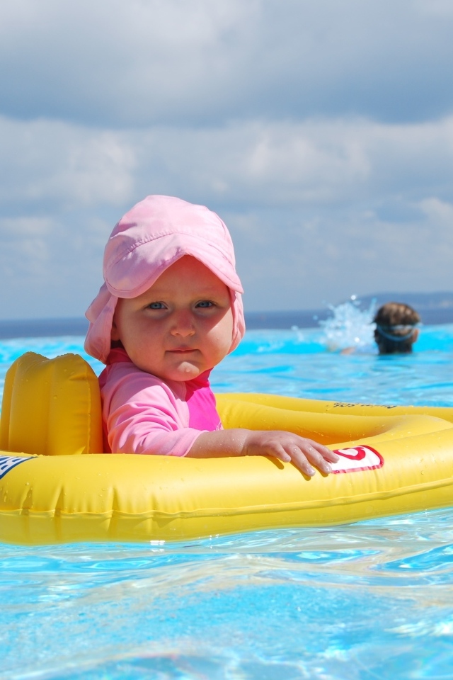 Ребенок со спасательным кругом плавает в бассейне
