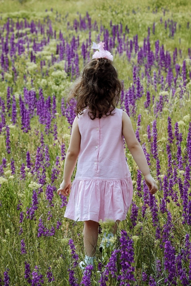 Девочка в розовом платье гуляет по полю с цветами