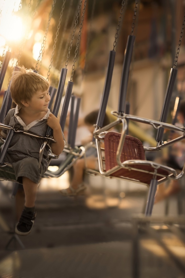 Маленький мальчик катается на каруселях