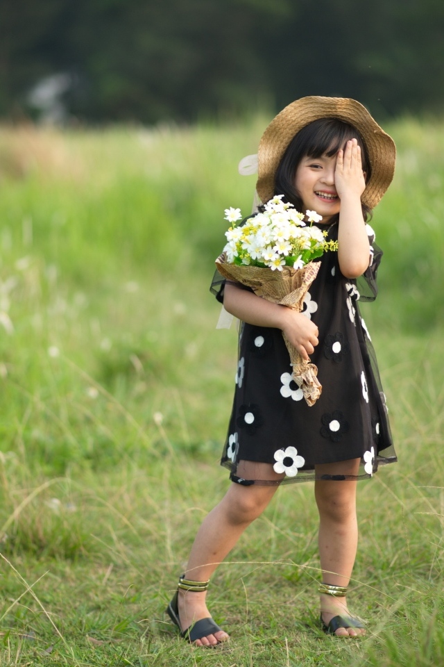 Девочка азиатка в шляпе с букетом цветов