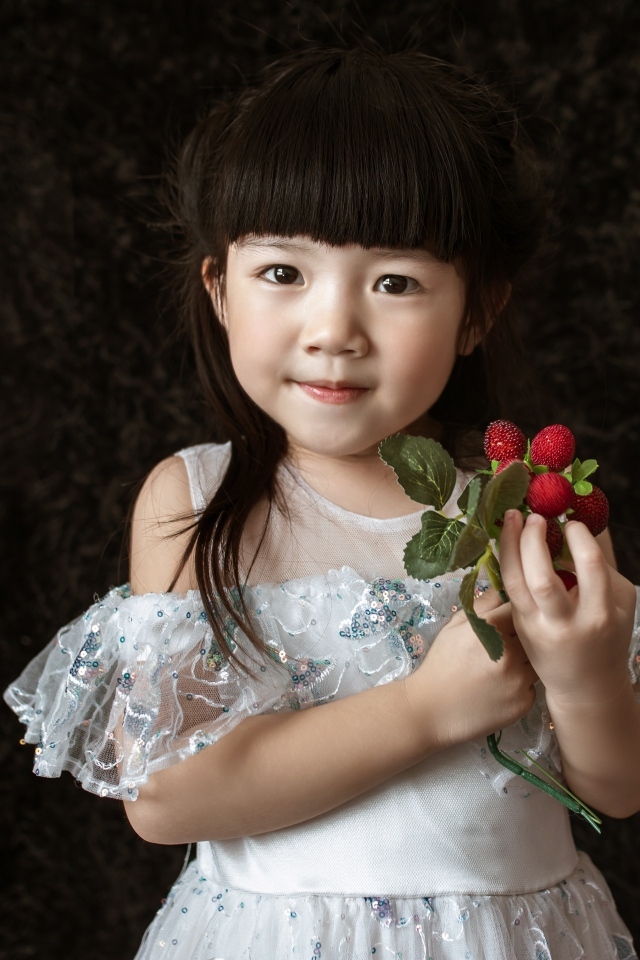 Девочка азиатка в белом платье с ягодами в руке